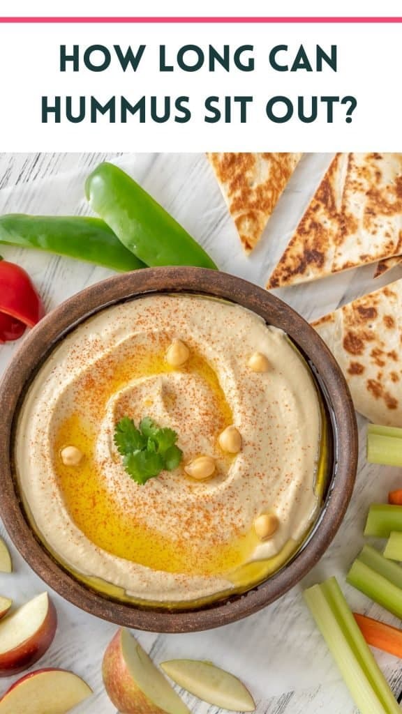 a bowl of hummus on a white table with apple slices, celary sticks, carrots sticks, bell peppers and pita with text that says how long can hummus sit out