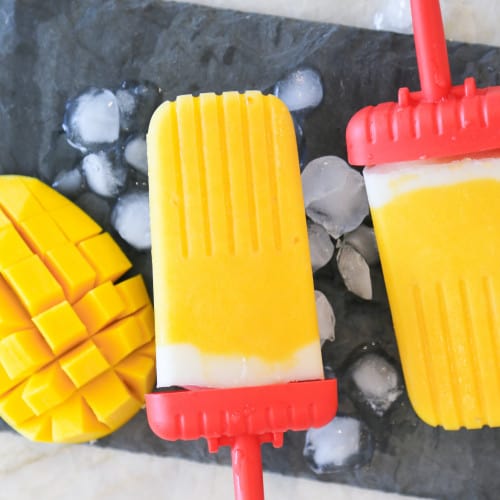 homemade mango popsicles with ice and cut up mango