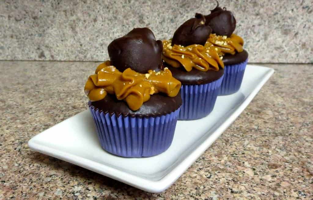 three snickers cupcakes on a plate 