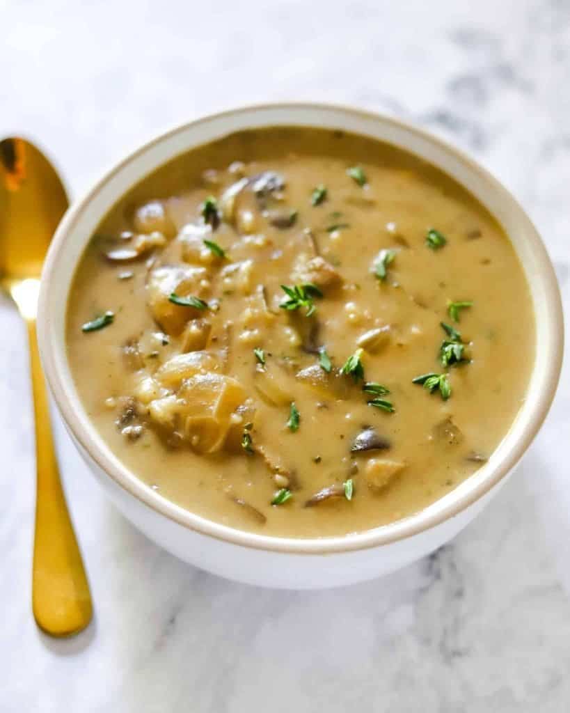 creamy mushroom soup in a white bowl with a spoon