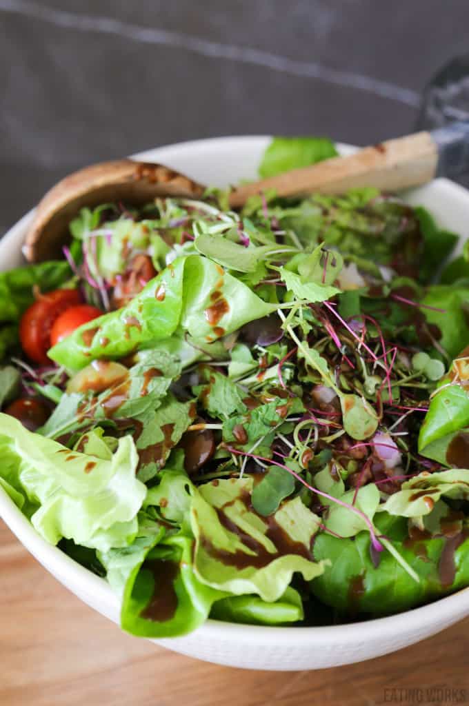 creamy balsamic salad dressing in a bowl with green salad sprouts and tomatoes