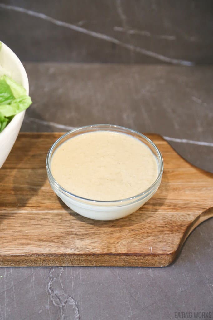 healthy caesar salad dressing recipe in a glass bowl on a cutting board