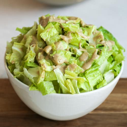 healthy caesar salad dressing recipe in a white bowl with romaine lettuce