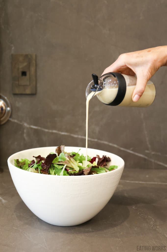 vegan Italian dressing recipe pouring into a salad in a bowl