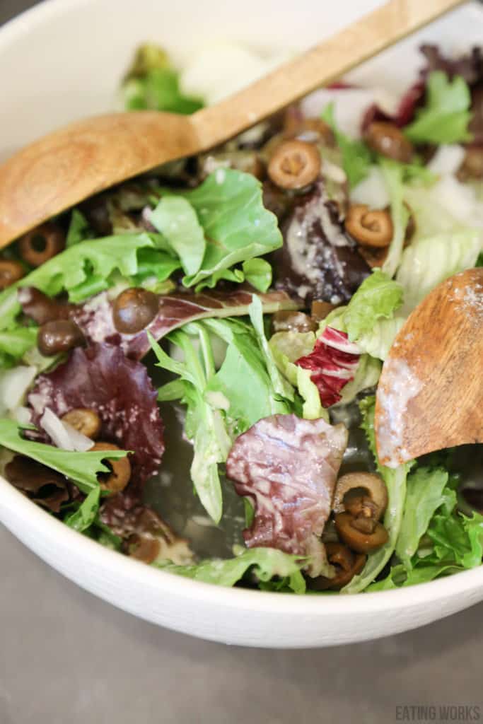 creamy vegan Italian dressing on a salad with olives in a bowl