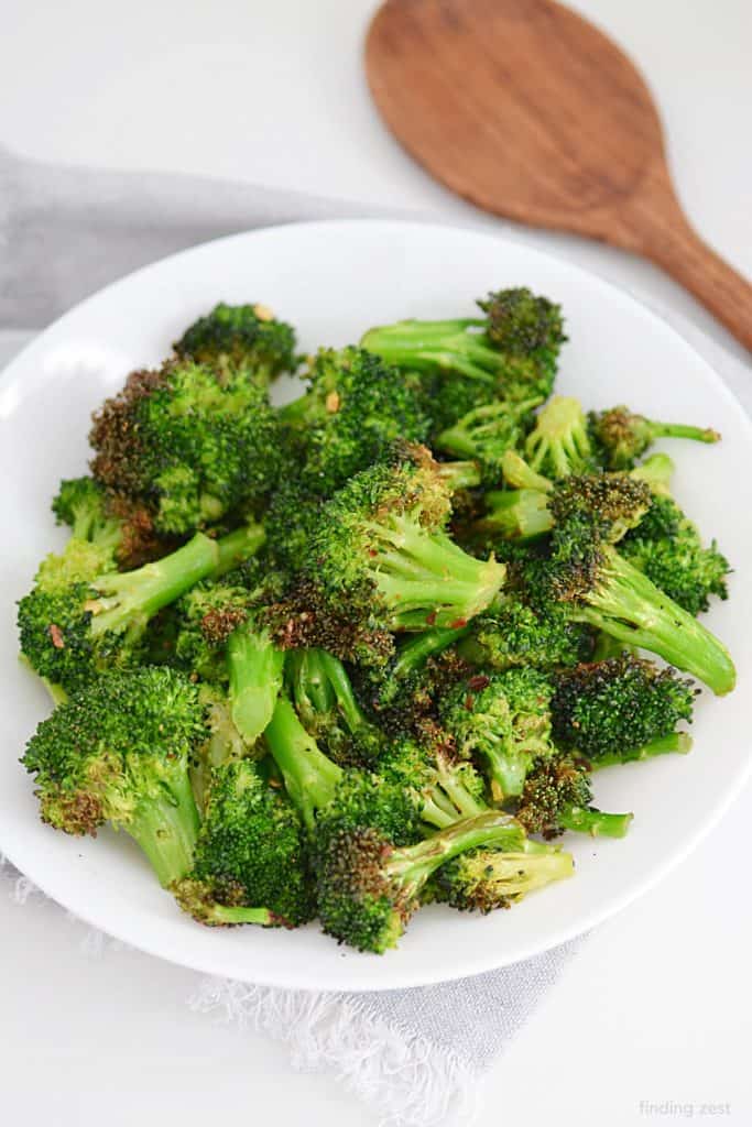 air fryer broccoli on a plate with a wooden spoon