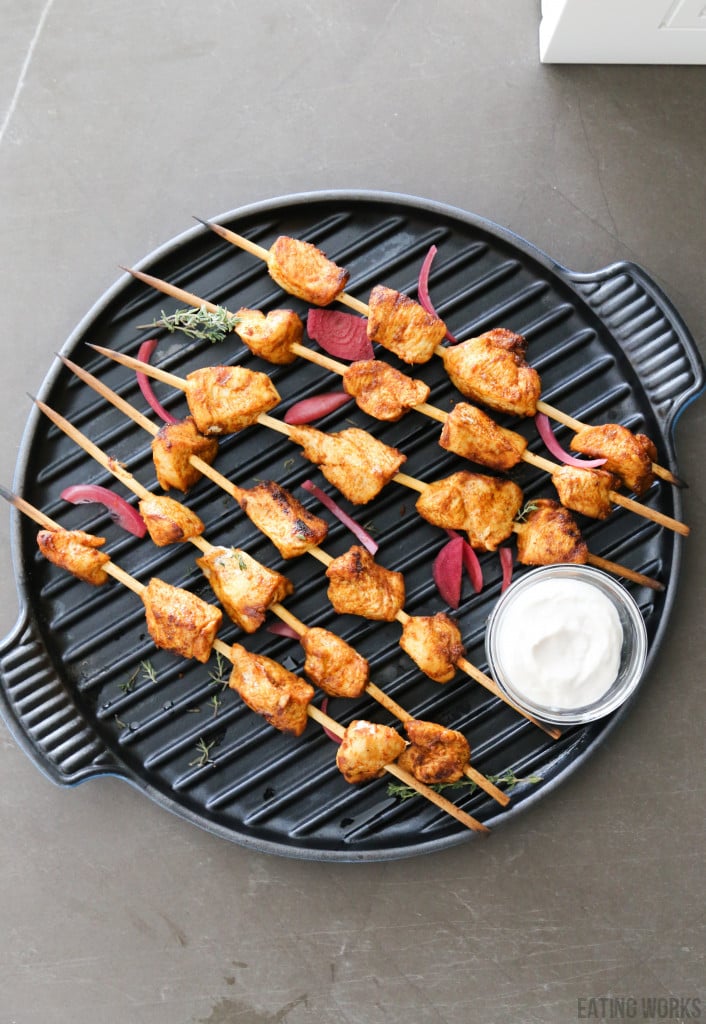 Peruvian style chicken oven kabobs on a grill pan with pickled red onions and a white dipping sauce