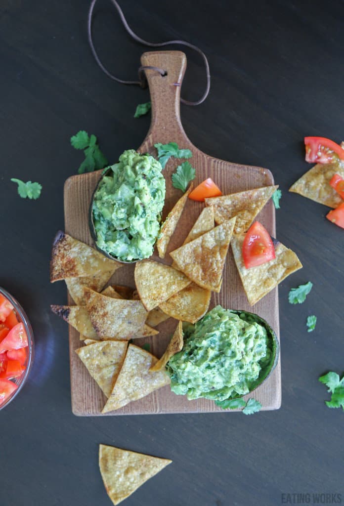 guacamole recipe without tomatoes on a cutting board with homemade tortilla chips