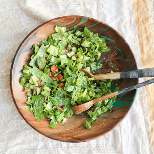 keto friendly greek salad in a wooden bowl with serving spoon and fork