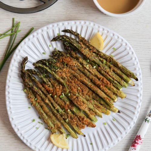 air fryer asparagus on a plate with lemon wedges