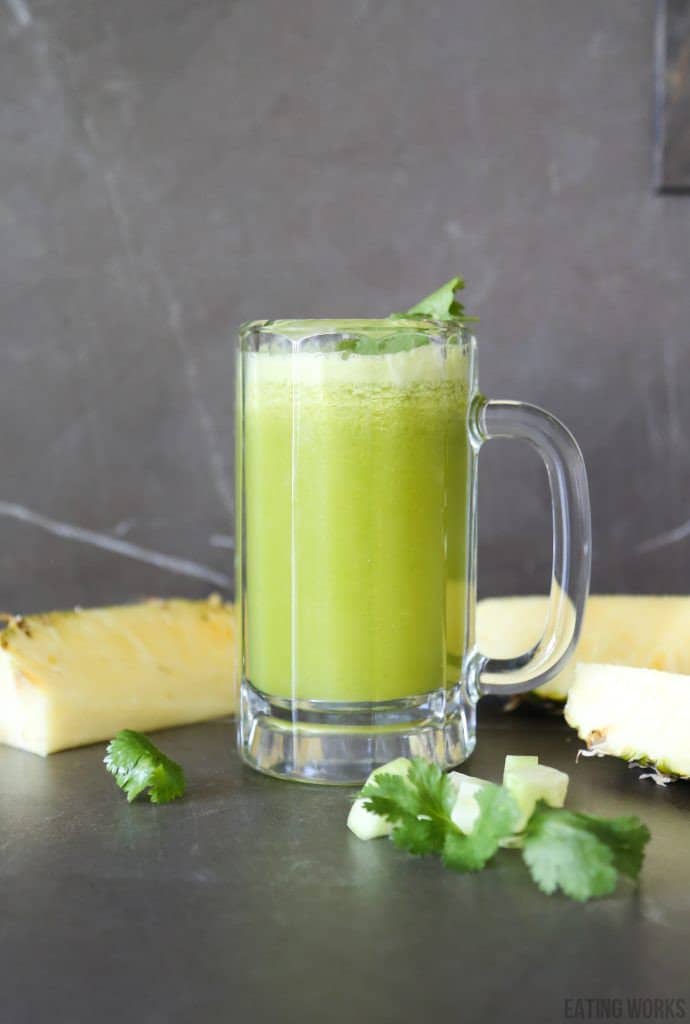 Pineapple and cucumber detox juice in a beer glass with chunks of pineapple and cucumber
