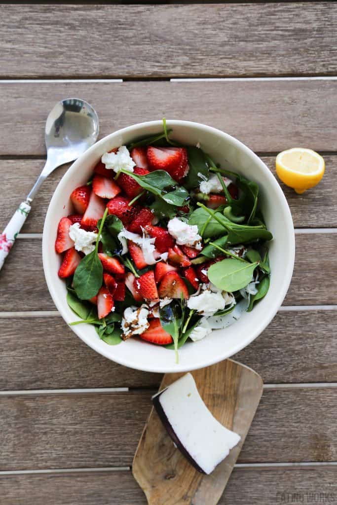 strawberry and goat cheese salad with a lemon and cheese on a cutting board