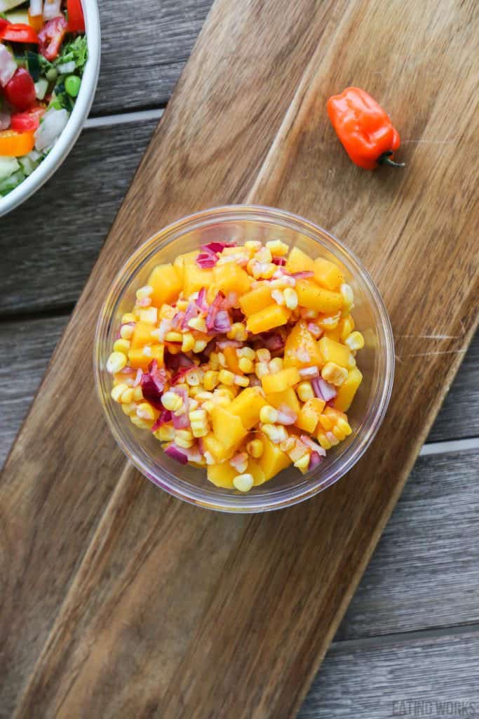 mango corn salsa in a glass bowl on a cutting board 