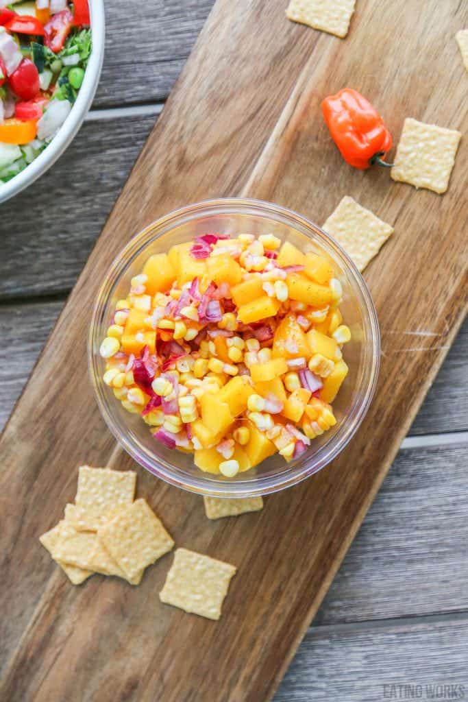 bowl of mango corn salsa with chips and peppers on the table