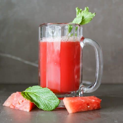 watermelon mint juice in a glass with mint leaves and watermelon chunks