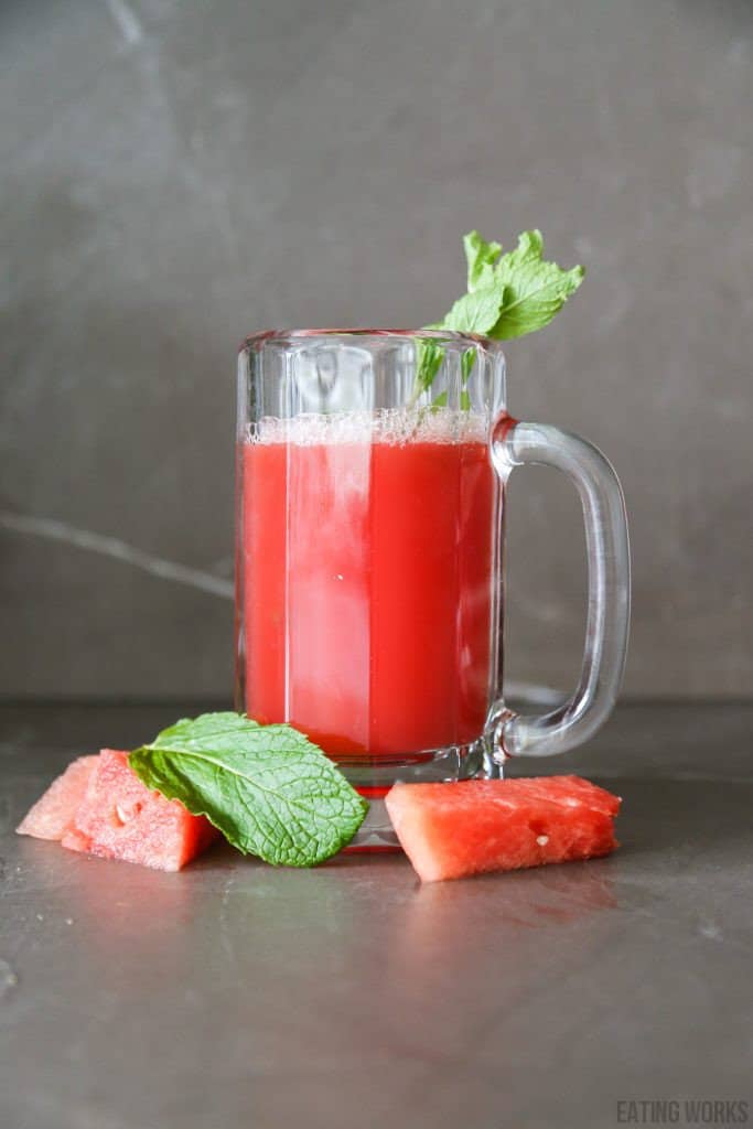 watermelon mint juice in a glass with mint leaves and watermelon chunks