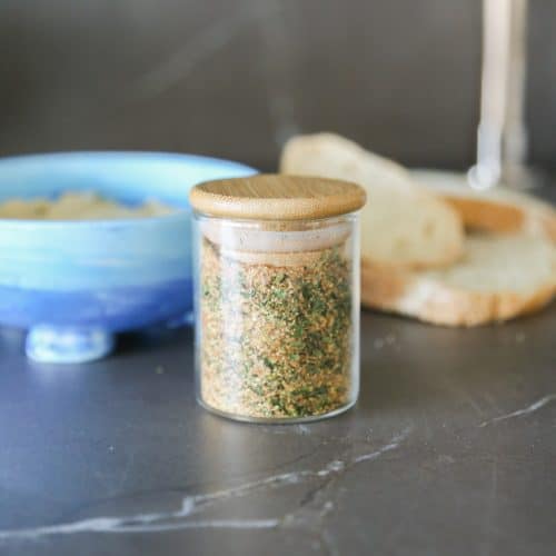 Mediterranean spice blend in a jar with bread and a bowl of butter