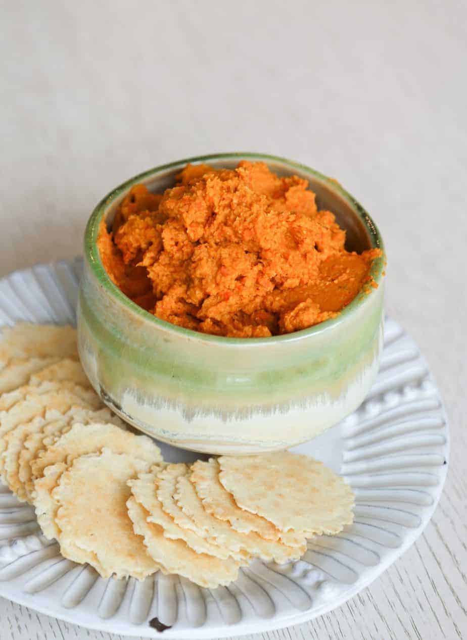 Gluten free hummus in a green bowl on a white plate with chips. Dips for charcuterie boards.