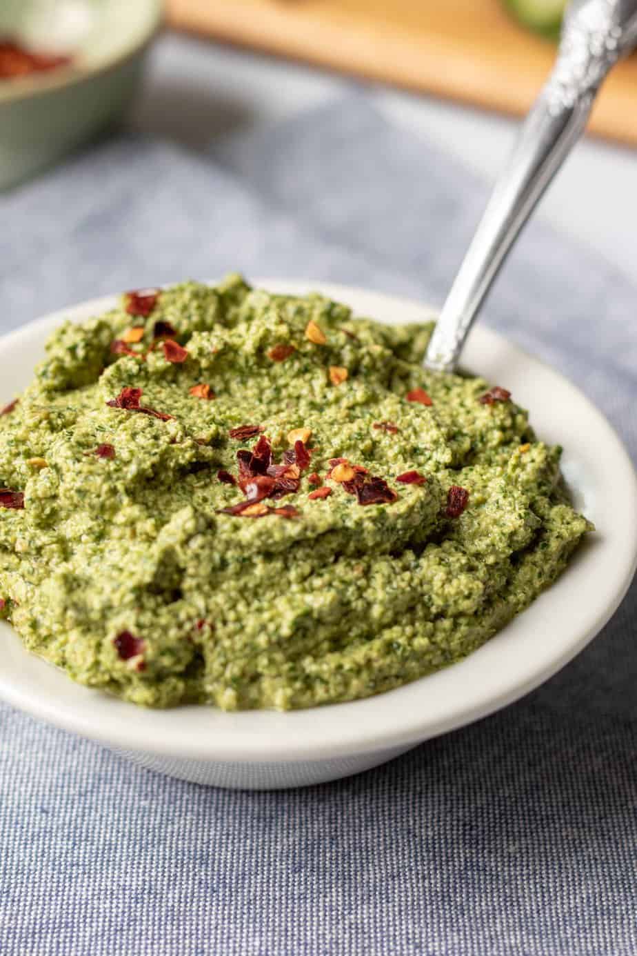 Colorful green zhoug sauce in a small bowl. Dips for charcuterie boards.