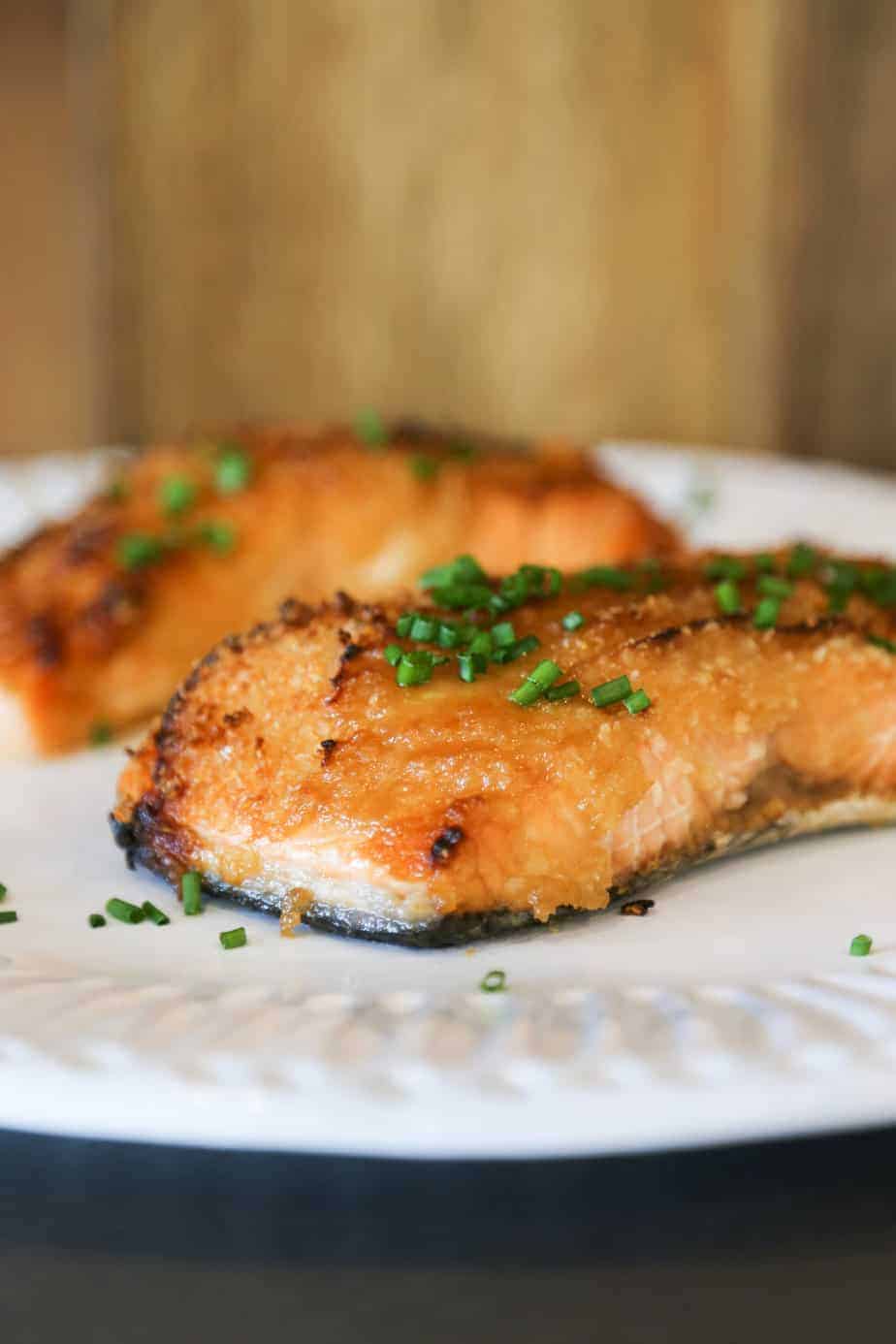 Air fryer salmon with dijon mustard sauce on a plate with chives.