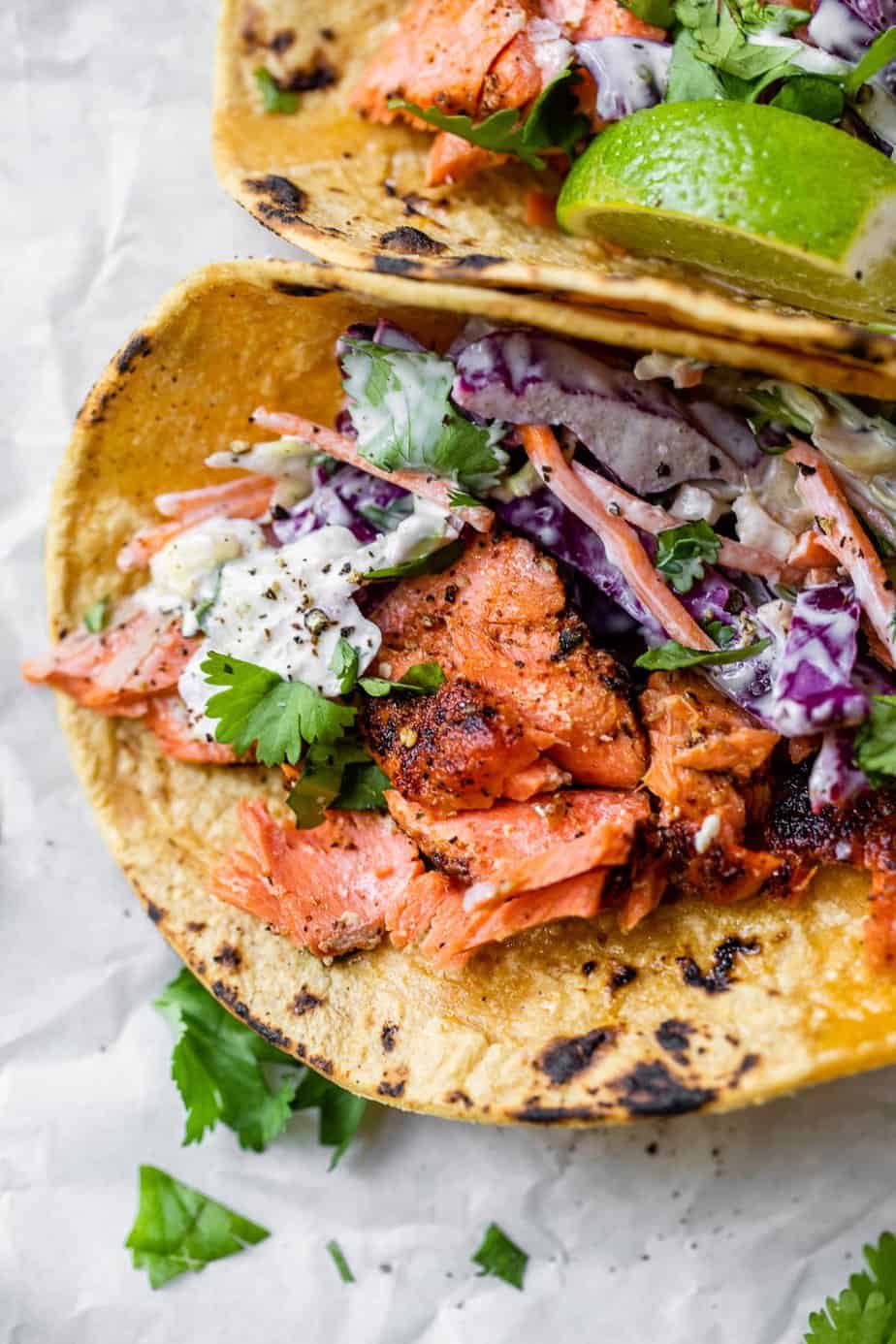 Easy salmon tacos in a corn tortilla topped with fresh cilantro leaves.