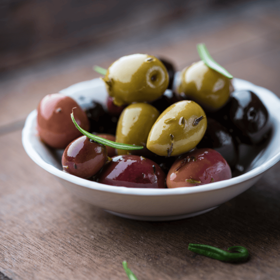 A bowl of marinated olives on a wooden table.