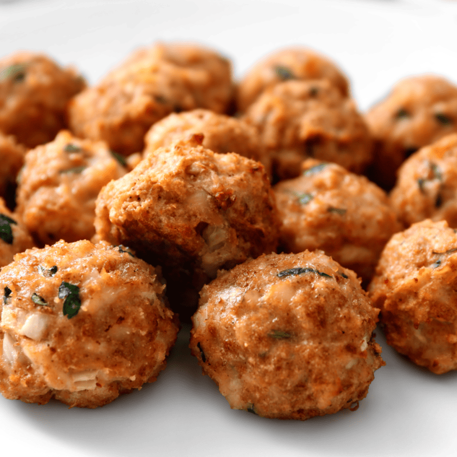 A close up of Italian meatballs on a white plate.