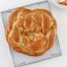 vegan round challah on a baking rack on a white table